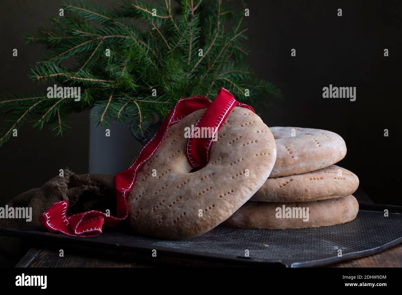 Pane rotondo con un buco al centro, uno è legato da un nastro rosso. Pane vecchio stile setaccio di segale su un foglio di metallo. Su un tavolo marrone retrò, con una v Foto Stock