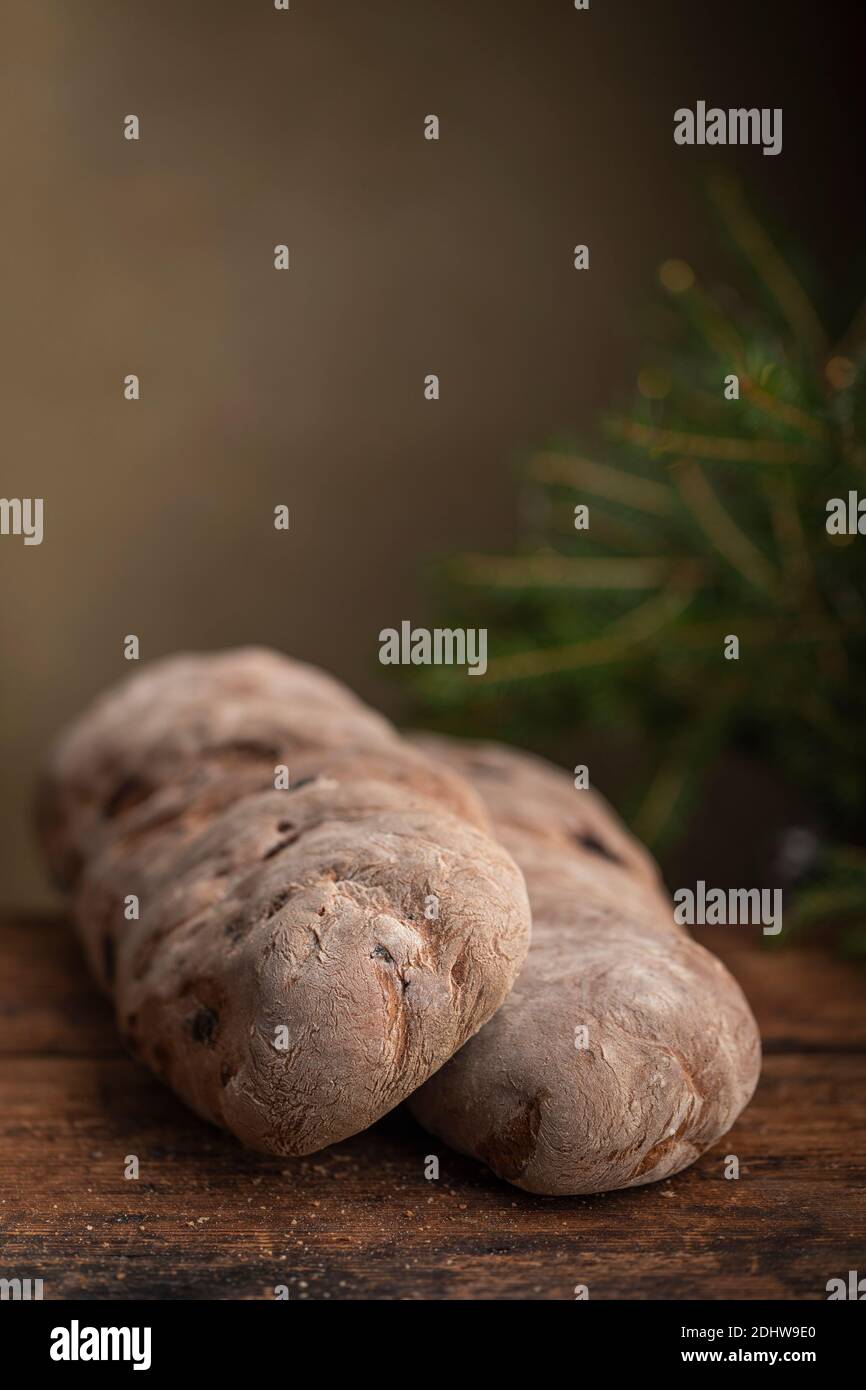 Vörtbröd pane di segale con uvetta su un tavolo di legno. Con rami pinaceae sullo sfondo. Il pane tradizionale svedese di natale ha fatto il pane o il mosto lo Foto Stock