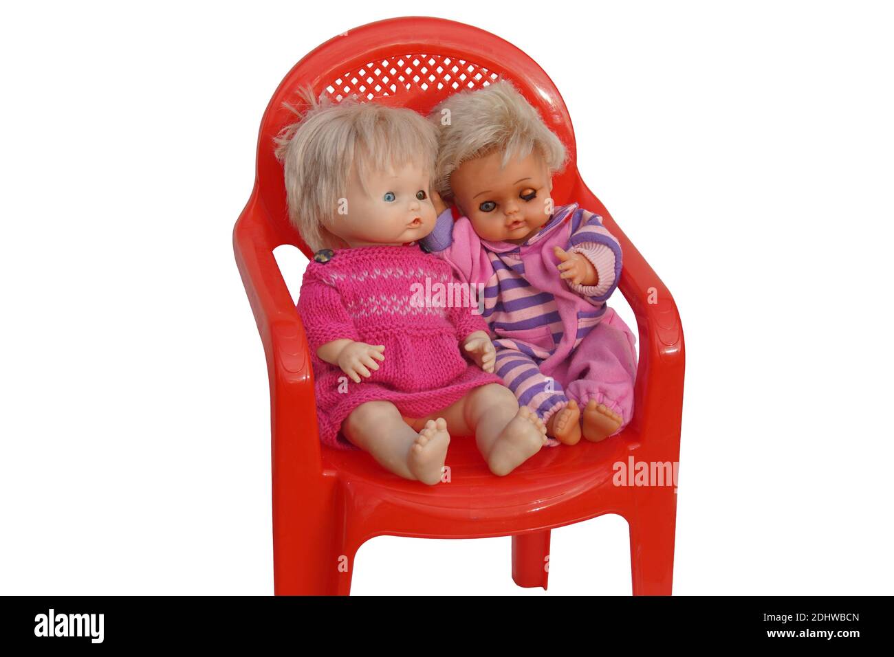 Due vecchie bambole sedute su una sedia di plastica rossa con sfondo  bianco. Una bambola con un abito lavorato a maglia e con un occhio  danneggiato. Isolato Foto stock - Alamy