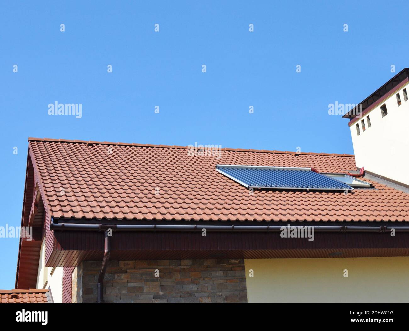 Primo piano del sistema di riscaldamento ad acqua solare sottovuoto, gocciolatoio sul tetto della casa in piastrelle rosse. Soal Energy for Energy Efficiency Modern House Building Concept. Foto Stock