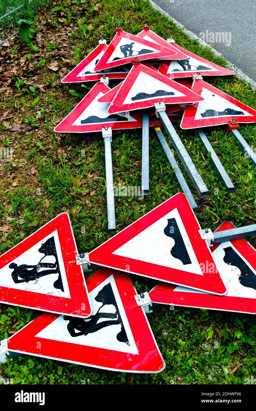 Viele Verkehrszeichen einer Strassenbaustelle liegen übereinander am Boden. Foto Stock