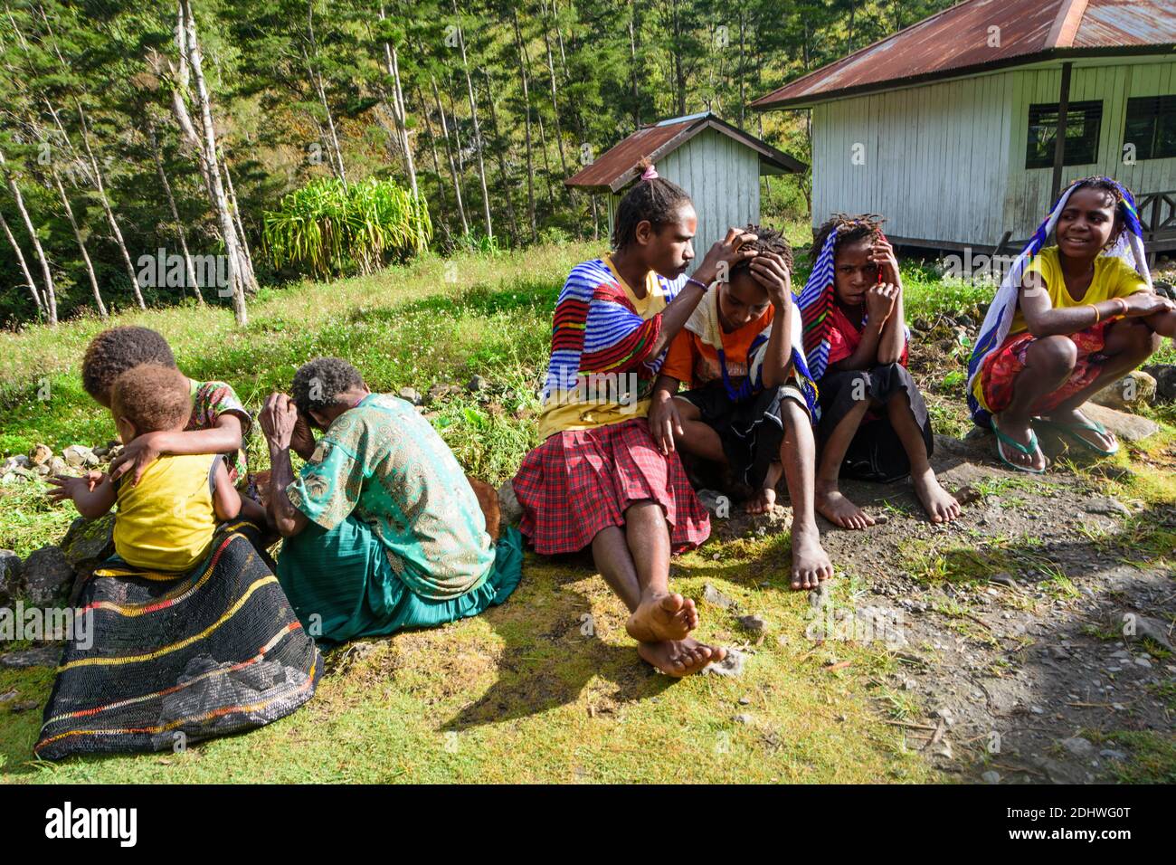 Un gruppo di giovani ragazze che si siedono a terra e socializzano in un villaggio Dani nella Valle di Baliem, Papua Occidentale, Indonesia Foto Stock