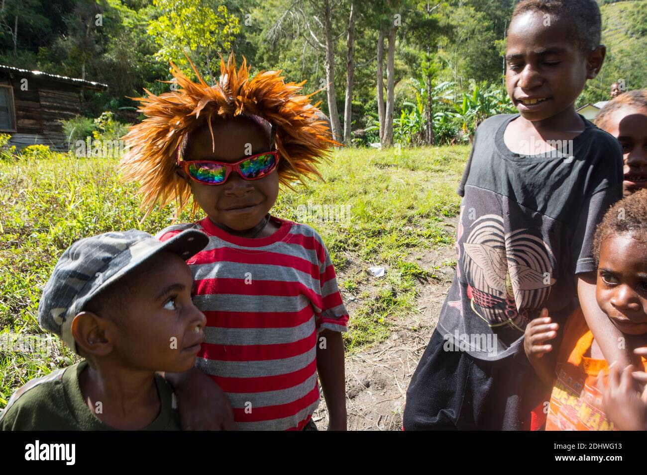 Giovane ragazzo con moderni occhiali da sole alla moda e tradizionale headdress insieme ai suoi amici in un villaggio nella valle di Baliem. Papua Occidentale, Indonesia Foto Stock