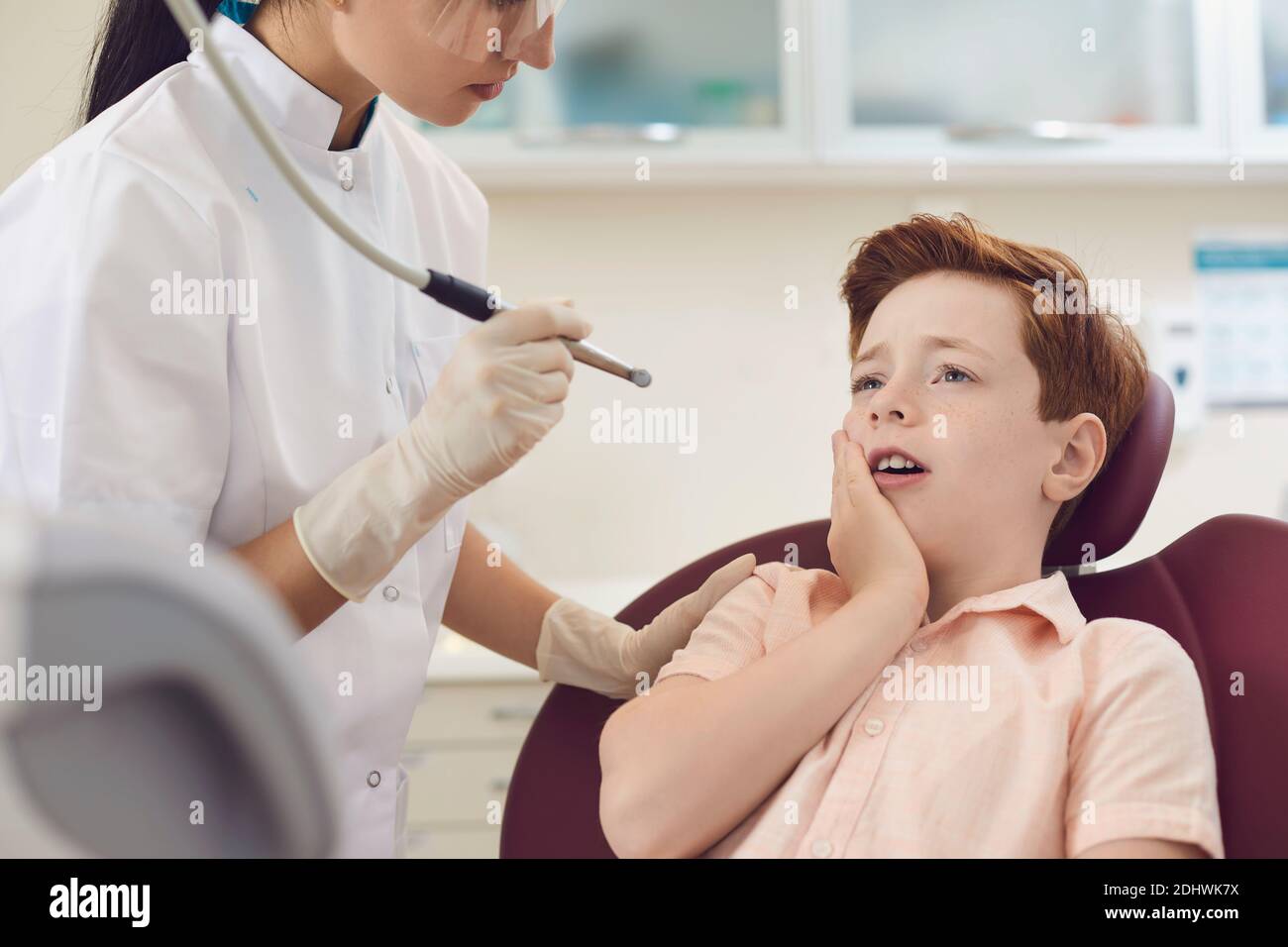 Ambulatorio dentale per bambini. Il ragazzino si siede su una sedia dentista e soffre di grave mal di denti. Foto Stock