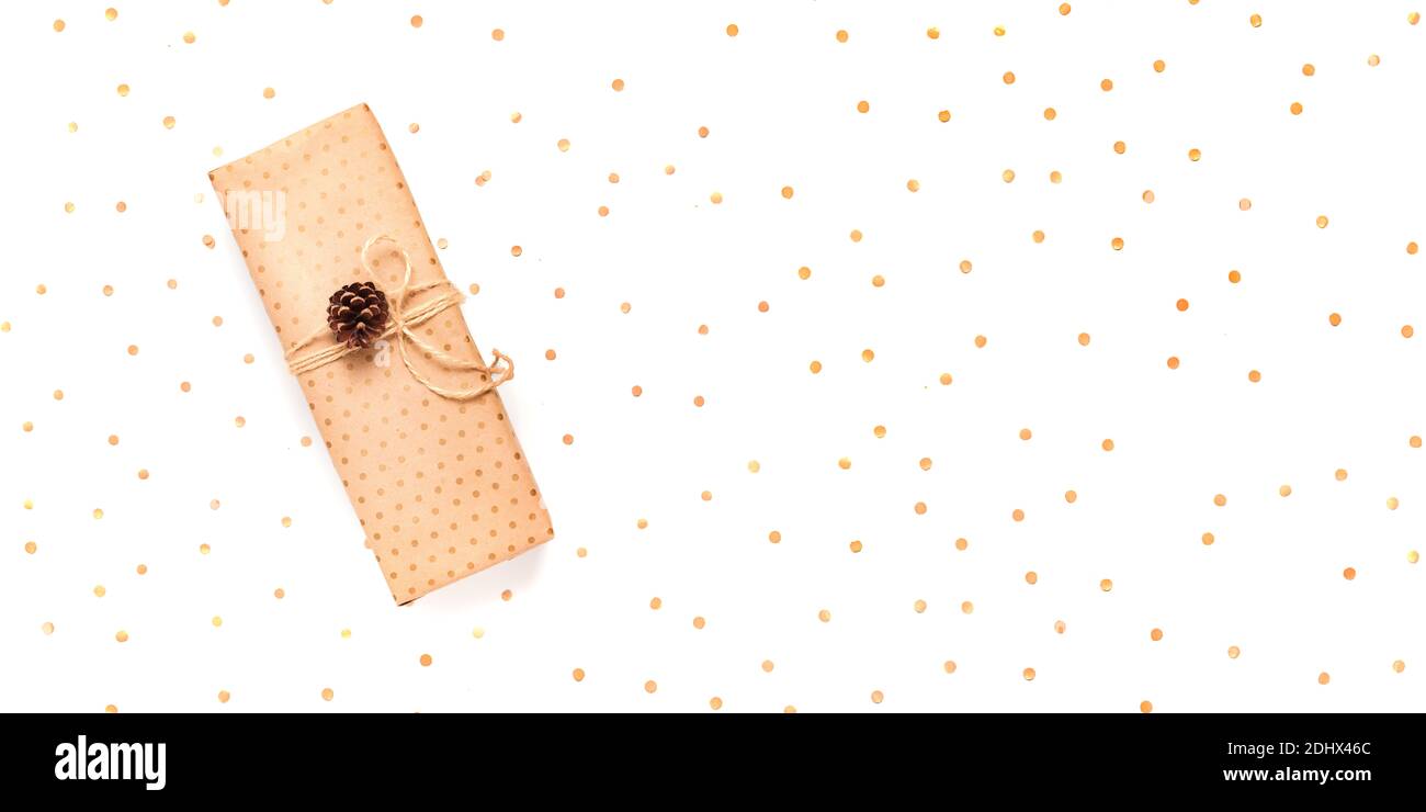 Confezione regalo avvolta in carta artigianale decorata con cono di pino su sfondo bianco, banner lungo, spazio copia, vista dall'alto Foto Stock