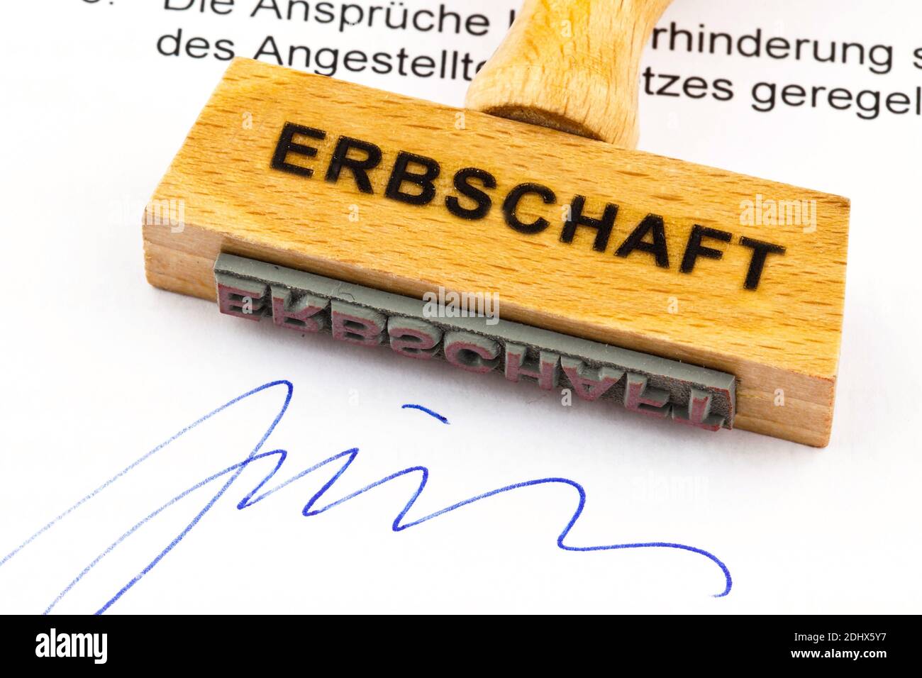 Ein Stempel aus Holz liegt auf einem Dokument. Deutsche Aufschrift: Erbschaft Foto Stock