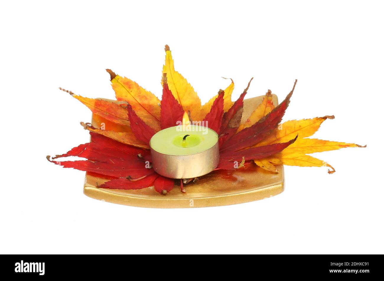 Decorazione autunnale tavolo, piatto d'oro con foglie di acer Autumnal e una luce da tè bruciante isolata contro il bianco Foto Stock