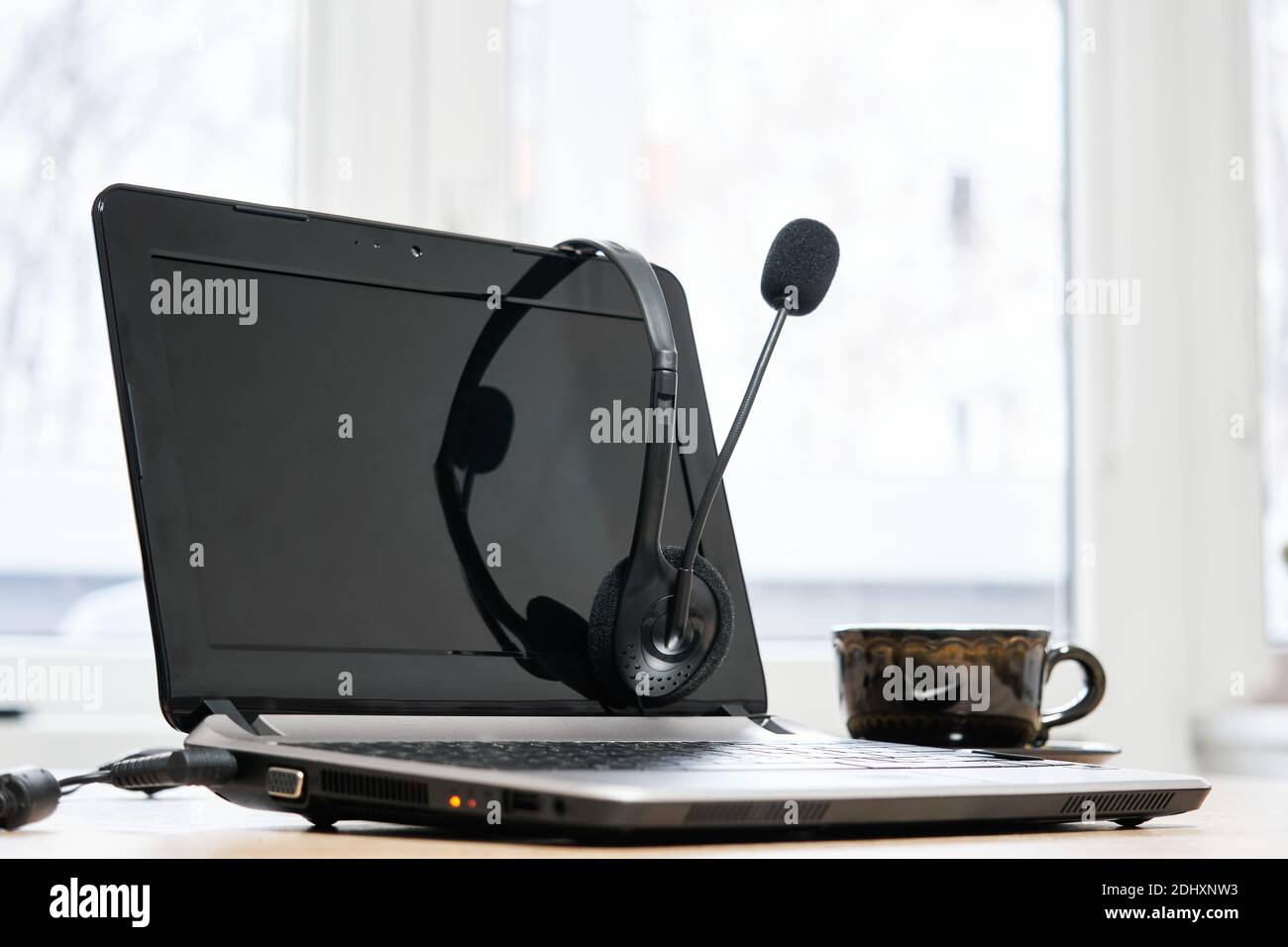computer portatile, cuffie con microfono e tazza da caffè sul tavolo da vicino Foto Stock