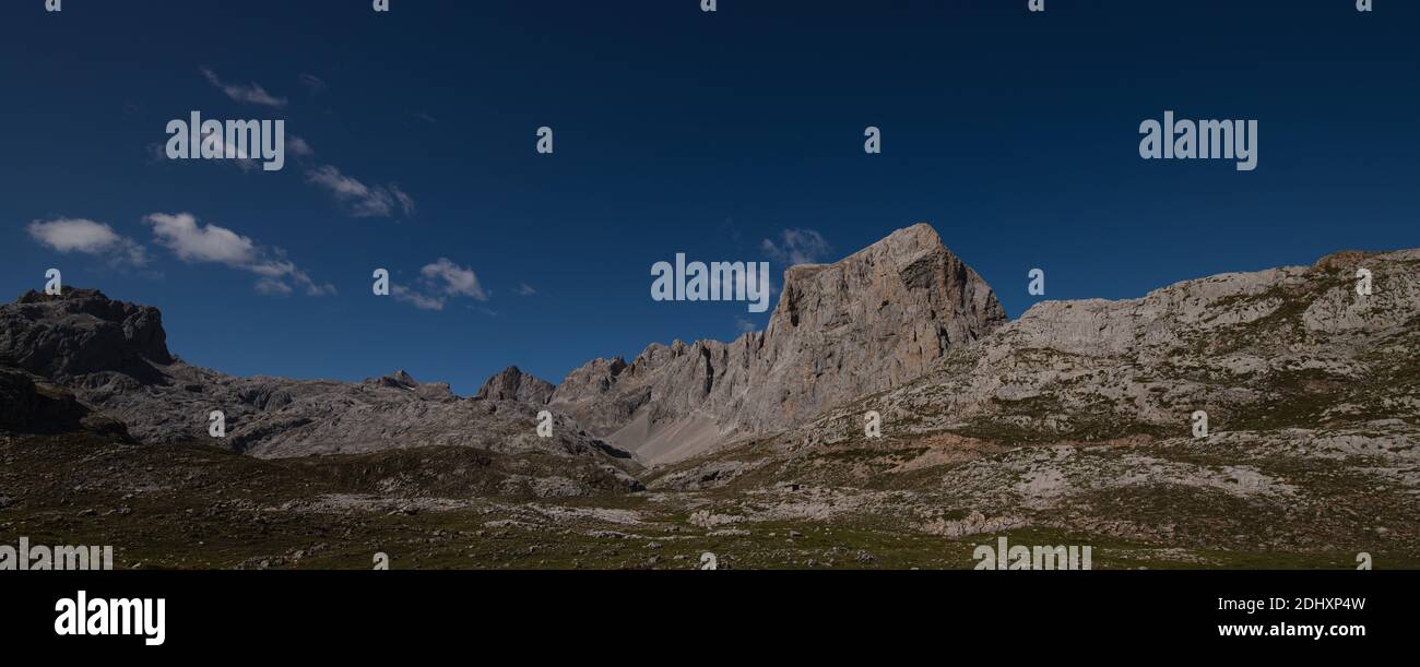 panorama delle cime grigie e della vegetazione sul terreno con cielo blu Foto Stock