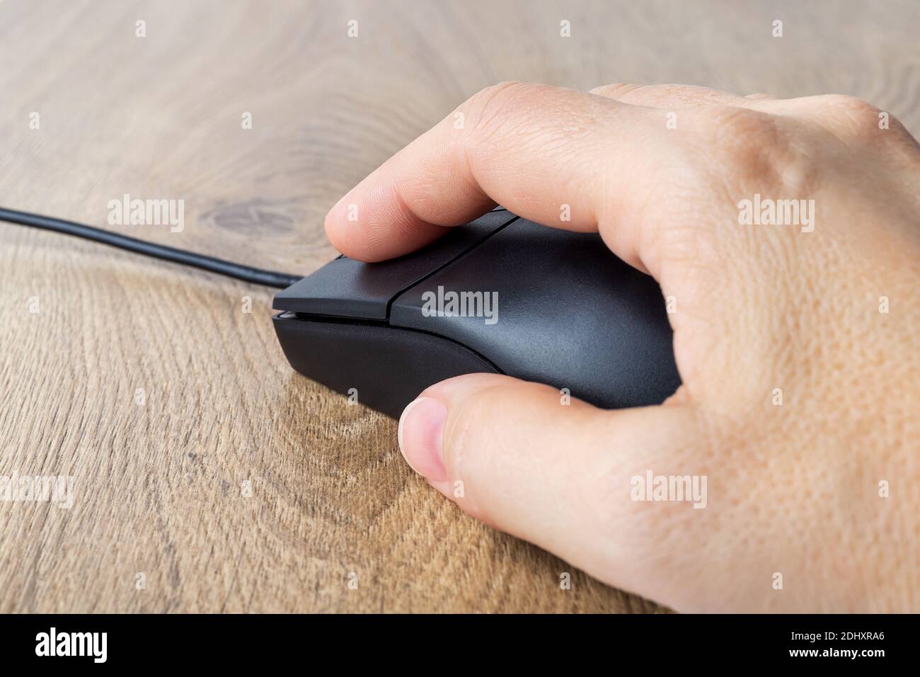 Donna caucasica palma su mouse ottico nero cablato su scrivania marrone. Lavoro o studio al computer a casa o in ufficio. Primo piano della vista in prima persona Foto Stock