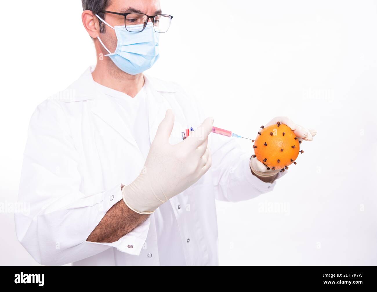 medico con il facciale filtrante facendo una vaccinazione contro un virus (cioè un arancione) Foto Stock