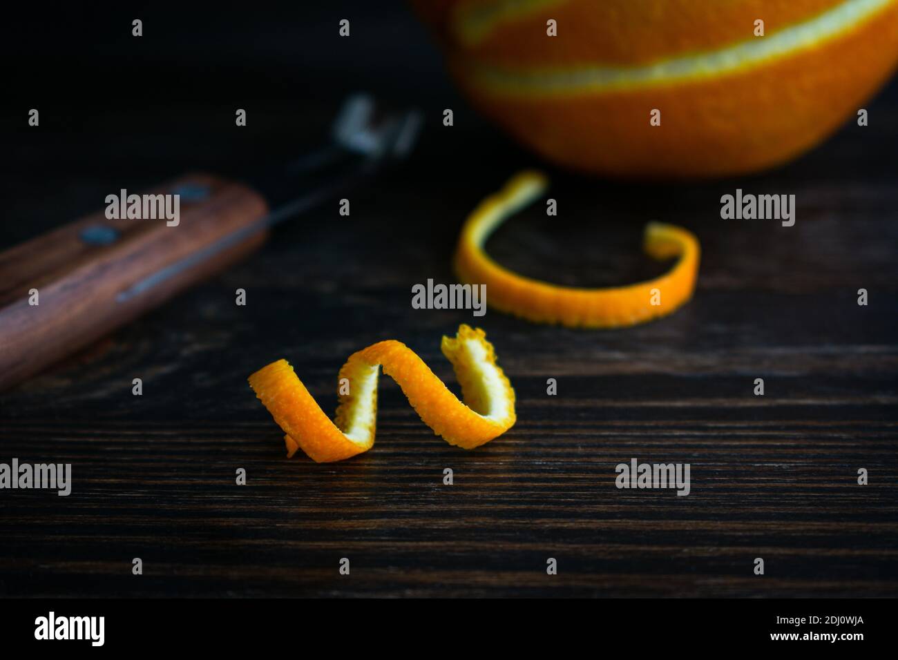 Arance Twist su un legno di squalo sfondo: Una striscia fresca di buccia d'arancia e un coltello canale Foto Stock