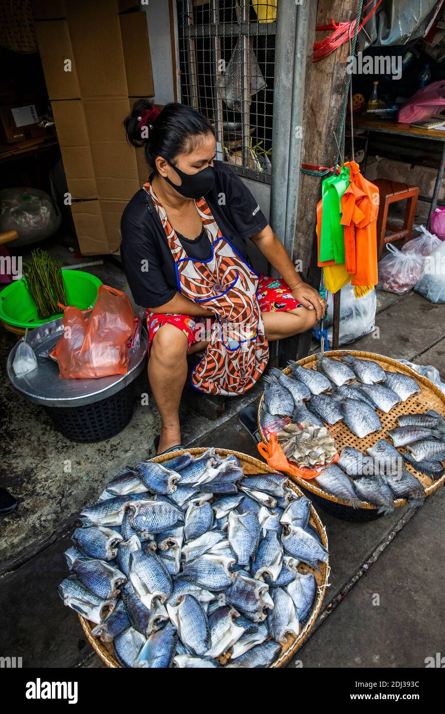 Una donna mercante nel mercato del treno di Mae Klong controlla la sua offerta di filetti di pesce fresco. Foto Stock