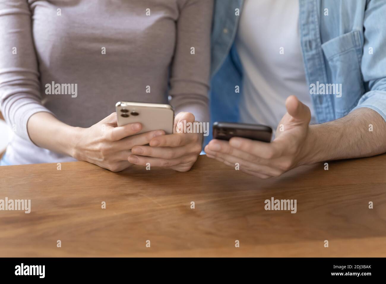 Primo piano coppia con smartphone, seduto al tavolo di legno Foto Stock