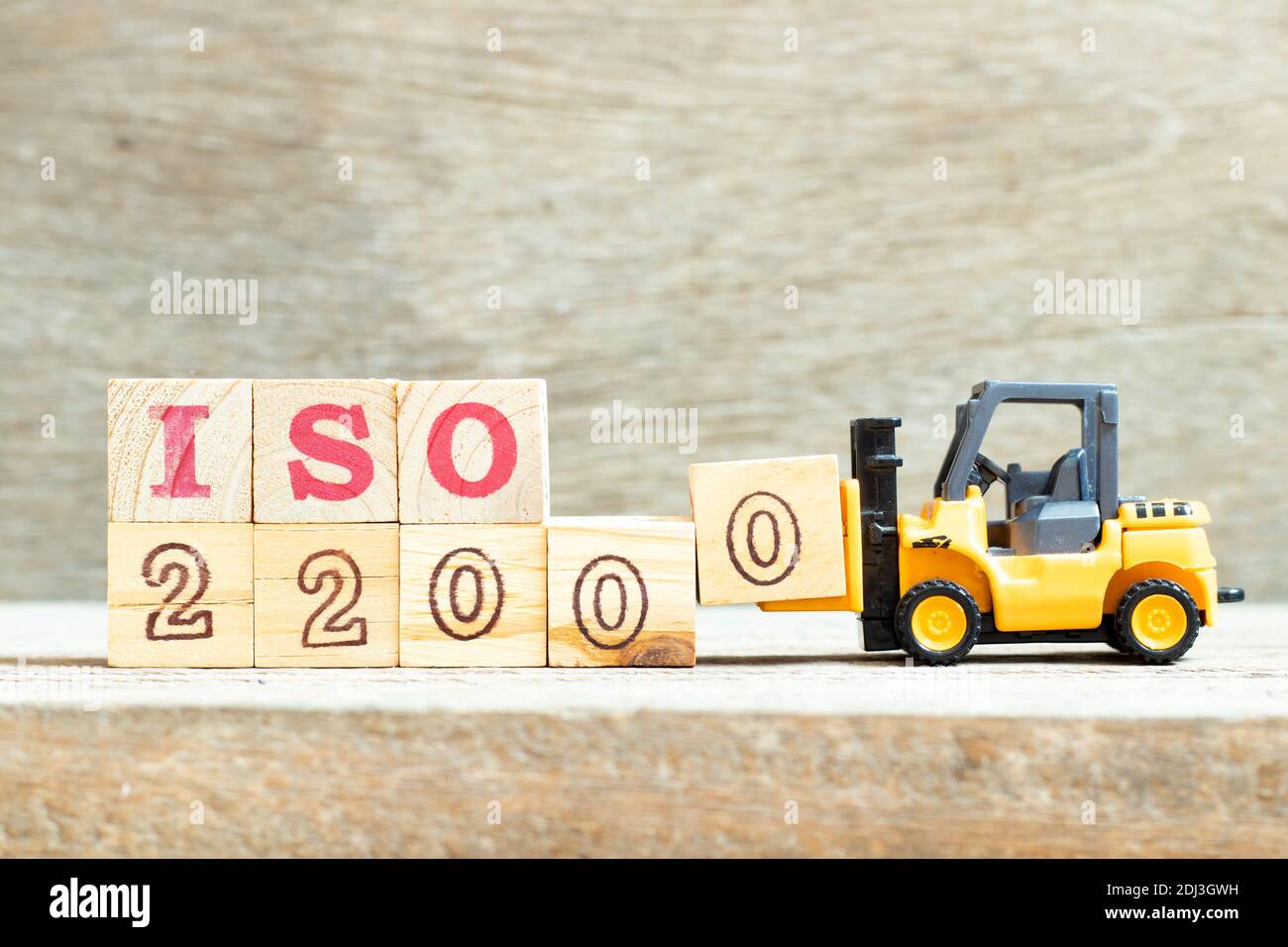 Carrello giocattolo tenere il blocco di lettera 0 per completare la parola iso 22000 su sfondo di legno Foto Stock