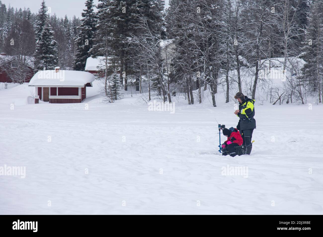 Levi, Lapponia, Finlandia - 6 marzo 2020: padre e figlio pescano sul lago ghiacciato di Levi. La pesca sul ghiaccio è così comune in Lapponia Foto Stock