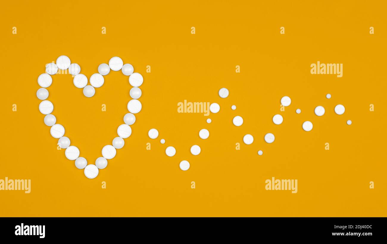 Background medico con pillole. Concetto di Giornata Mondiale del cuore. Background medico. Pillole bianche sotto forma di ritmi cardiaci e cardiaci su sfondo giallo piatto l Foto Stock