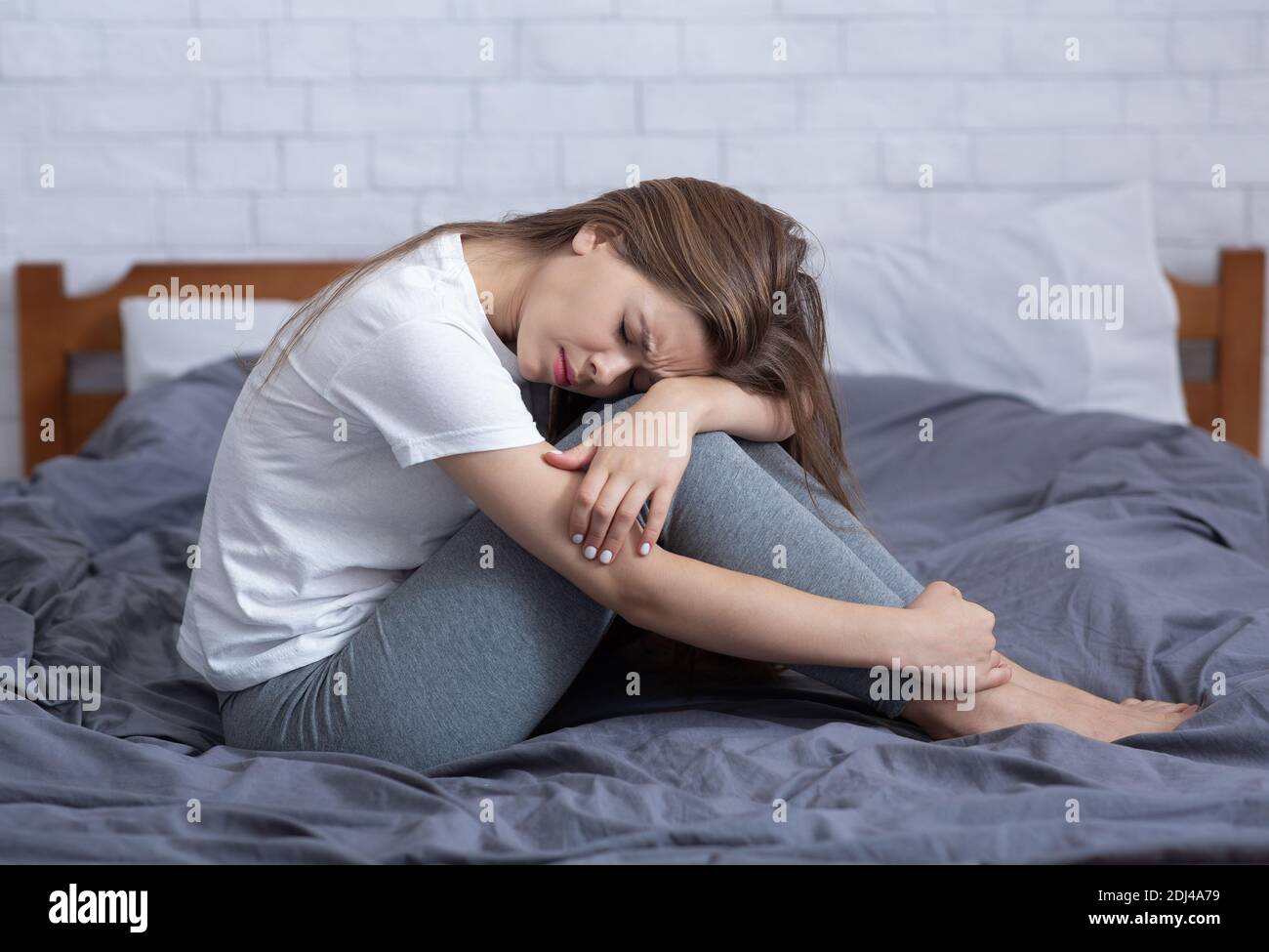 Giovane donna depressa seduta da sola nel suo letto, che soffre di solitudine o insonnia, che si sente infelice Foto Stock