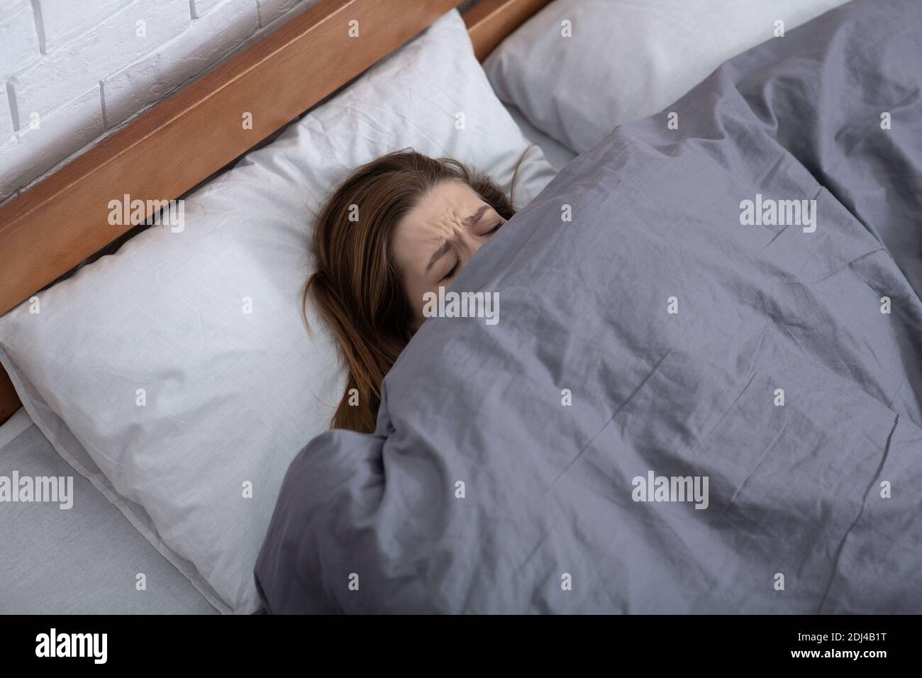 Concetto di salute mentale. Giovane donna depressa che si nasconde sotto coperta sul letto, soffre di depressione, stress o insonnia Foto Stock