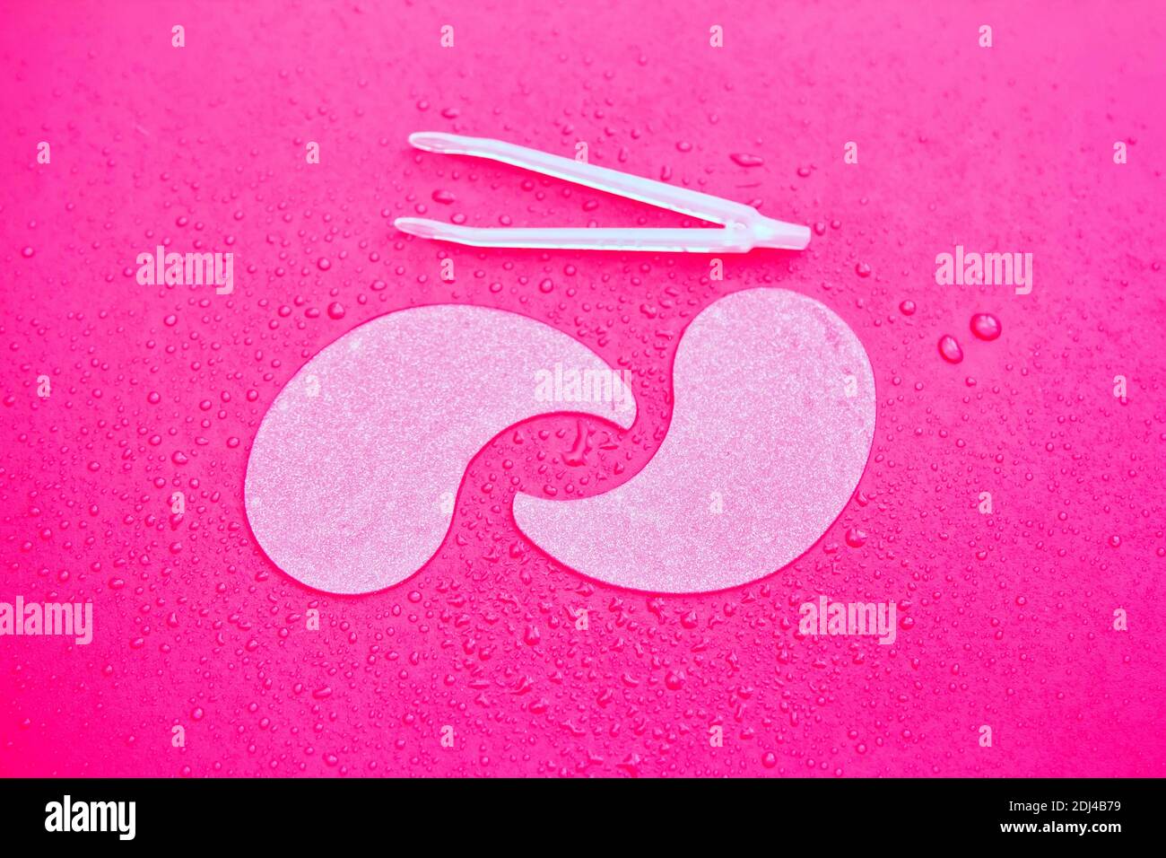 Idrogel cosmetico idratante collagene cerotti oculari su sfondo rosa con gocce d'acqua Foto Stock