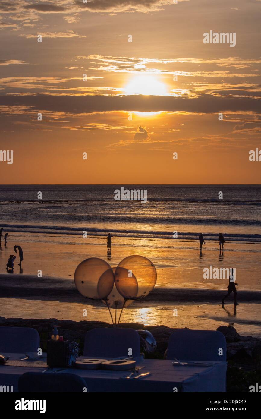 Venditori ambulanti su una spiaggia a Bali alla prova del tramonto per vendere i loro articoli Foto Stock