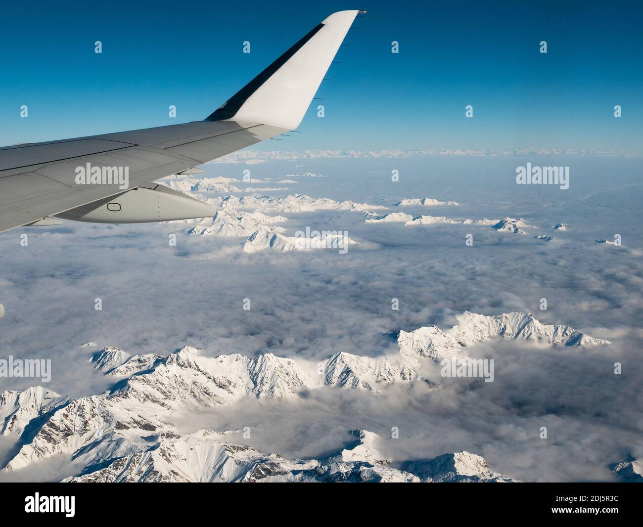 Vista aerea della Svizzera Italiana Alpi in inverno, con aereo generico di ala. Cime montagne e ghiacciai. Vista espansiva, cielo blu chiaro. Foto Stock