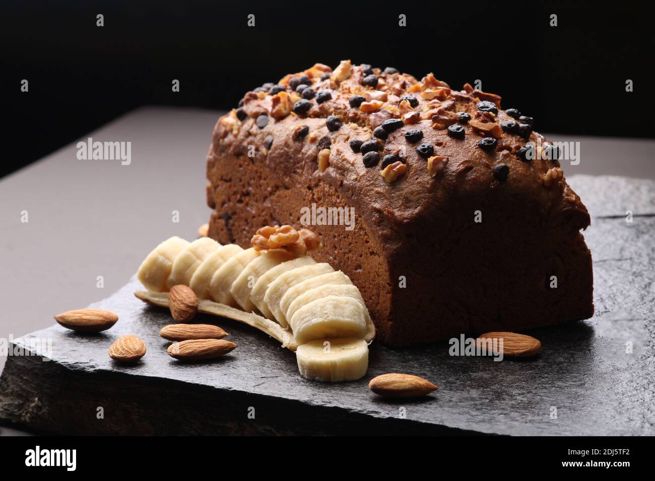 Pane di banana su fondo di pietra scura. Con mandorle e noce Foto Stock