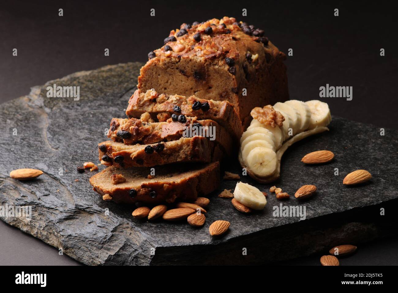 Pane di banana su fondo di pietra scura. Con mandorle e noce Foto Stock