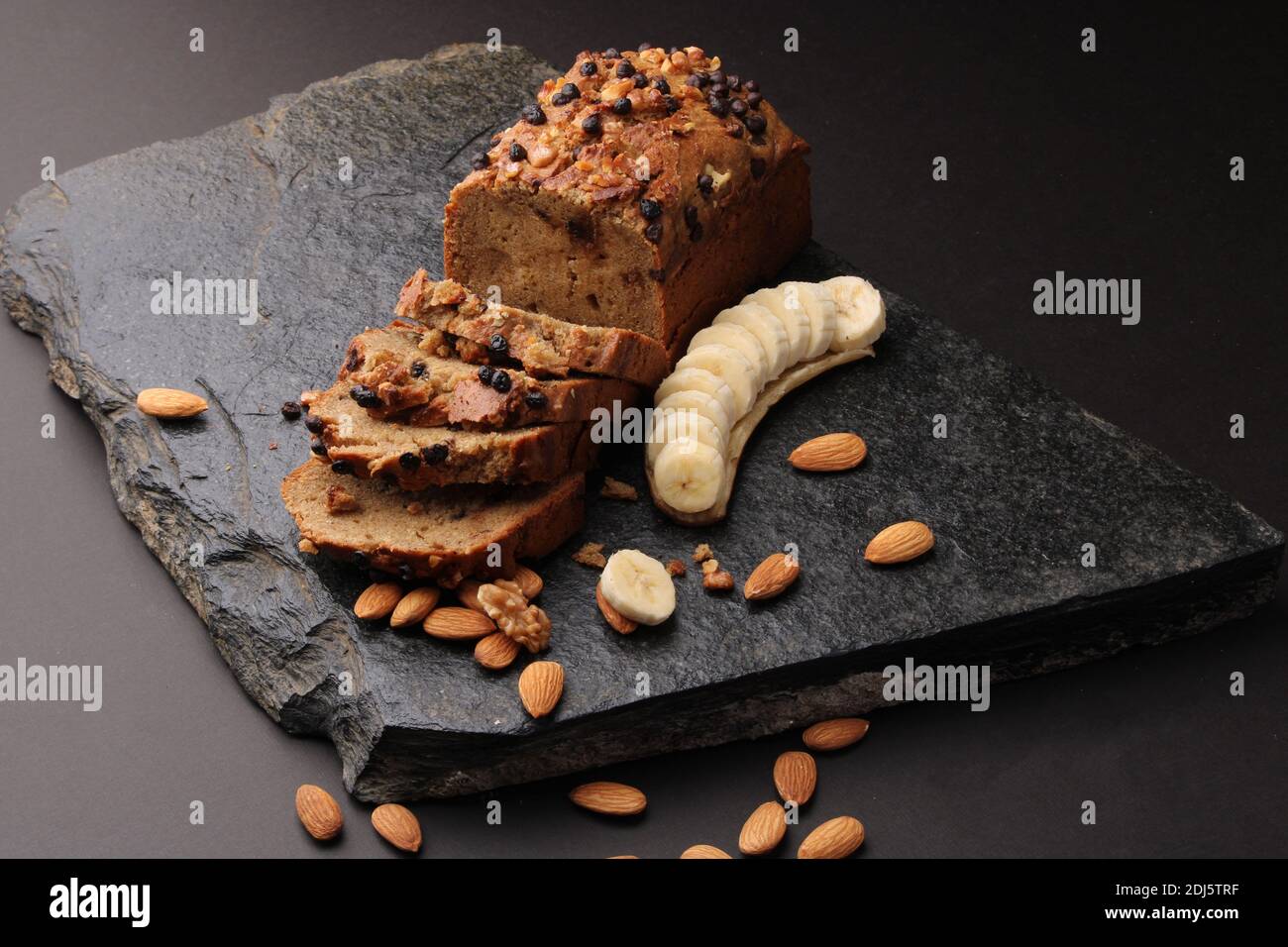 Pane di banana su fondo di pietra scura. Con mandorle e noce Foto Stock