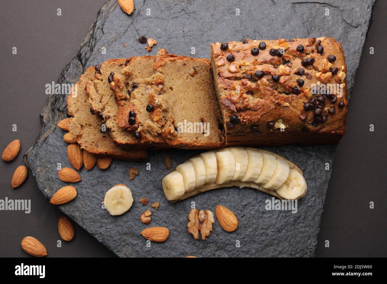 Pane di banana su fondo di pietra scura. Con mandorle e noce Foto Stock