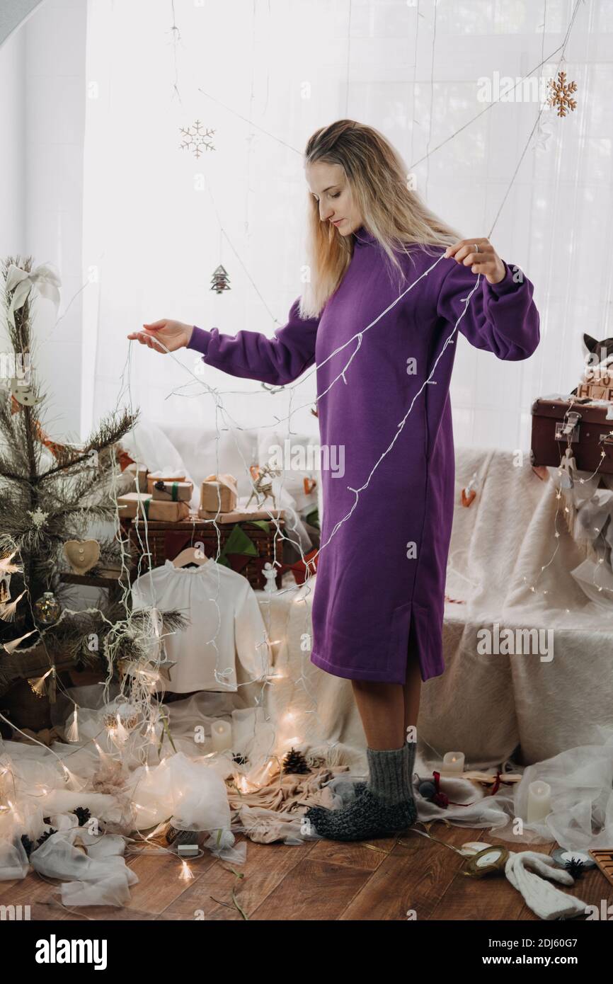 Natale decorazione a casa. Giovane donna che mette ornamenti sull'albero di Natale, mettendo le luci. Hristmas di bilancio idee di arredamento domestico Foto Stock