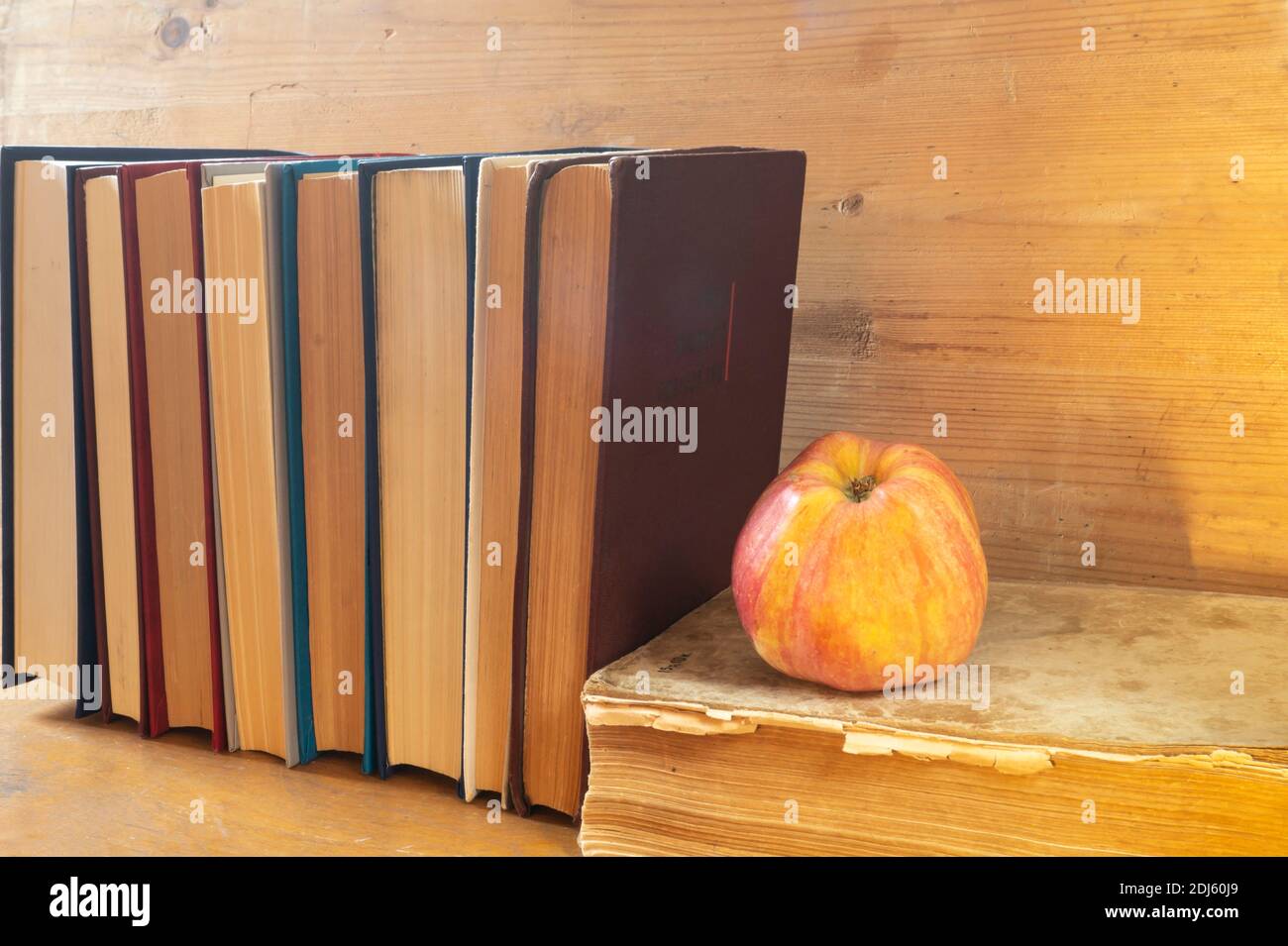 La mela rossa con il libro poggia su reggimento di legno. I soggetti in primo piano. Foto Stock