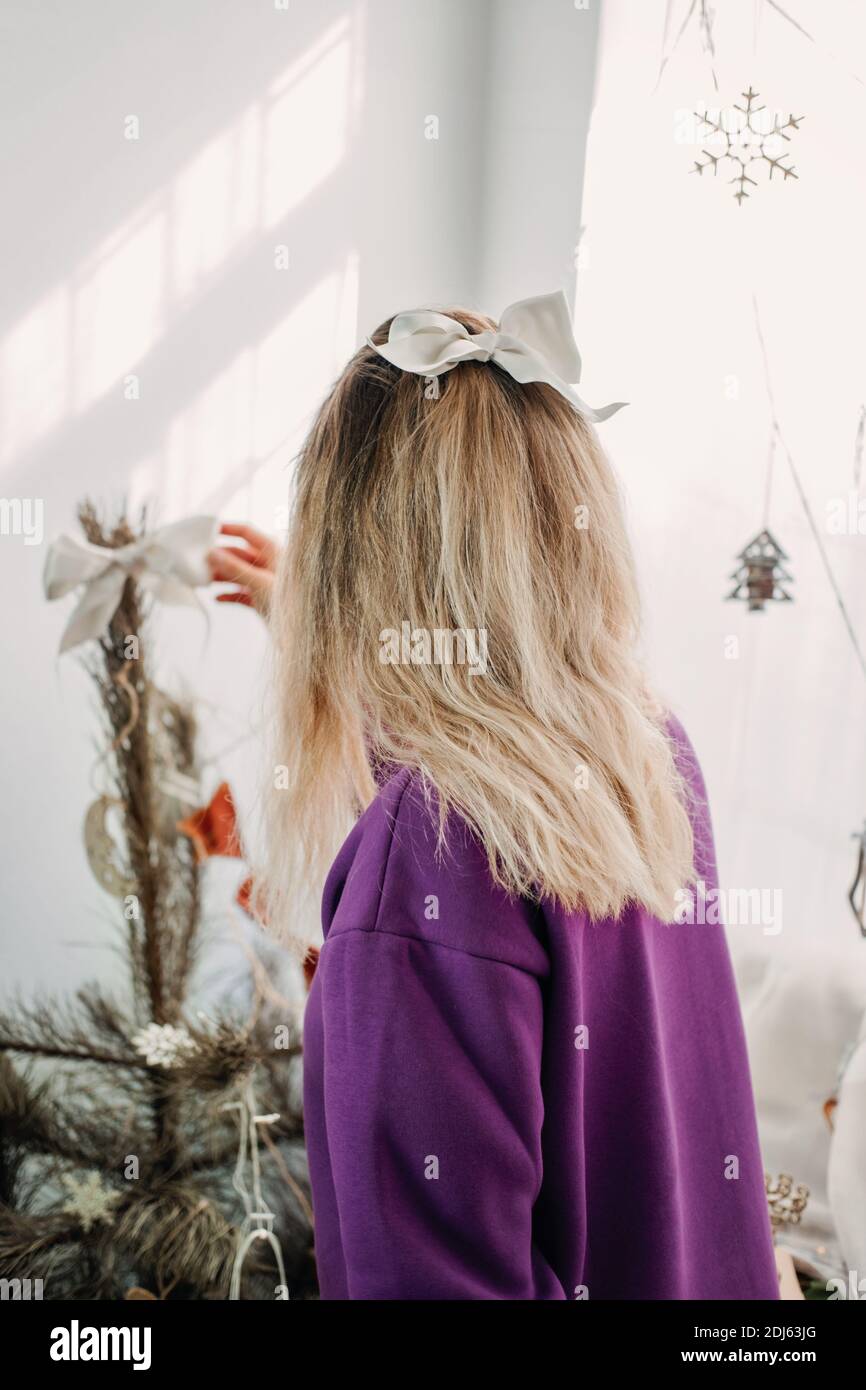 Natale decorazione a casa. Giovane donna che mette ornamenti sull'albero di Natale, mettendo le luci. Hristmas di bilancio idee di arredamento domestico Foto Stock
