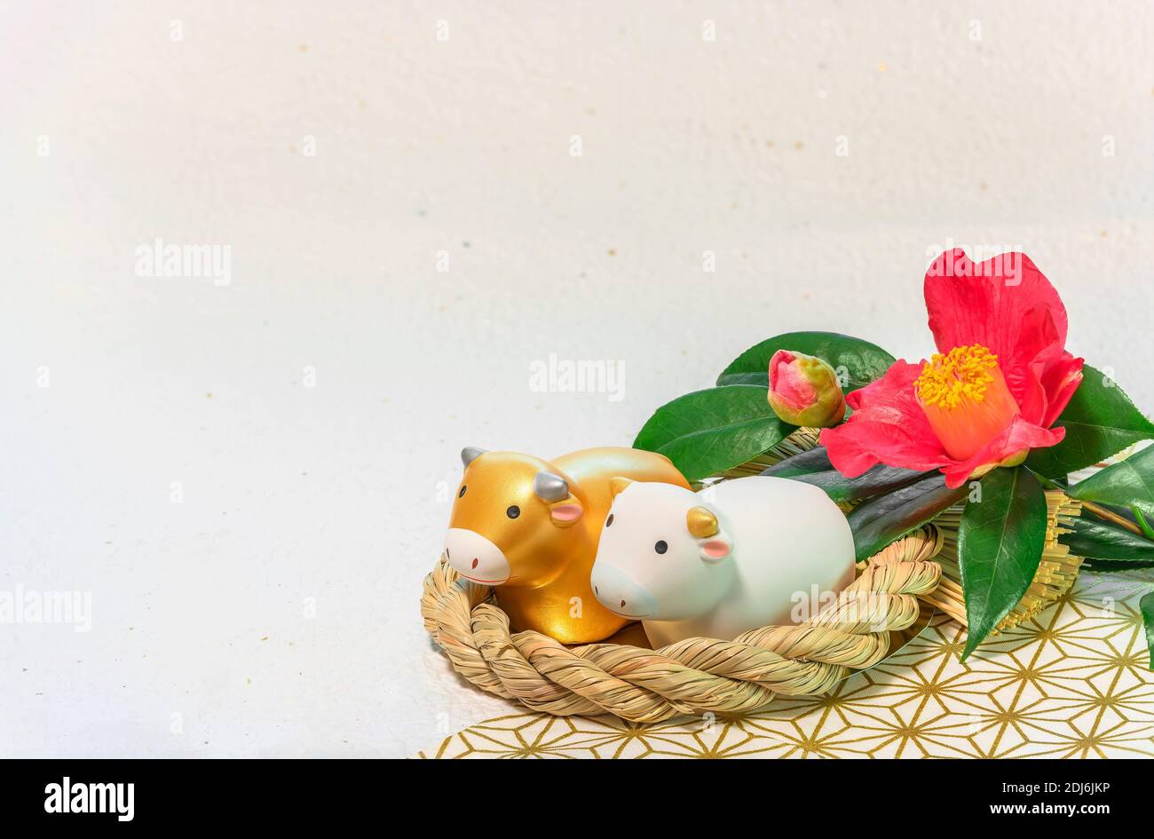 Biglietto d'auguri giapponese con un fiore Tsubaki chiamato l'inverno Rosa e due animali zodiacali figurine di mucche in A. Ornamento di paglia per l'anno del Foto Stock