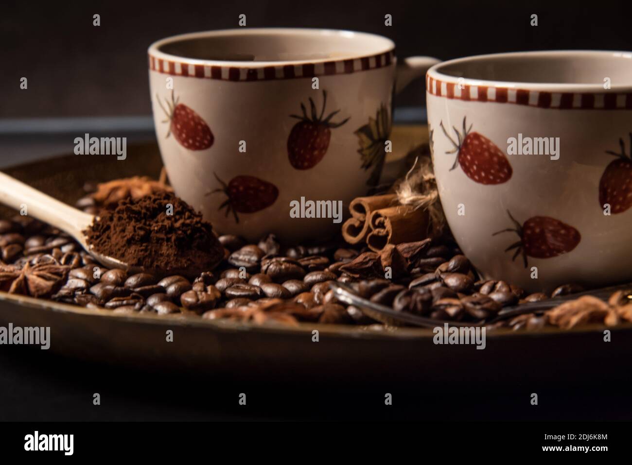 Due tazze di caffè su un vassoio dorato circondato da chicchi di caffè tostati, caffè macinato e spezie. Foto Stock