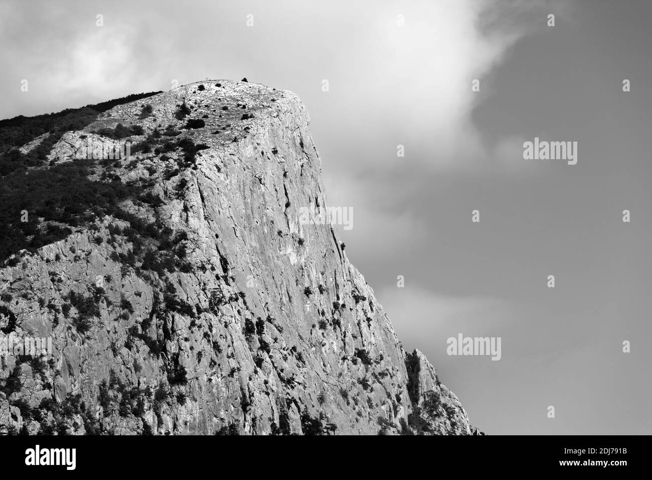 Altissime rocce estive con foresta e cielo nuvoloso. Cima del Monte Kush-Kaya. Crimea, Ucraina. Paesaggio in bianco e nero. Foto Stock