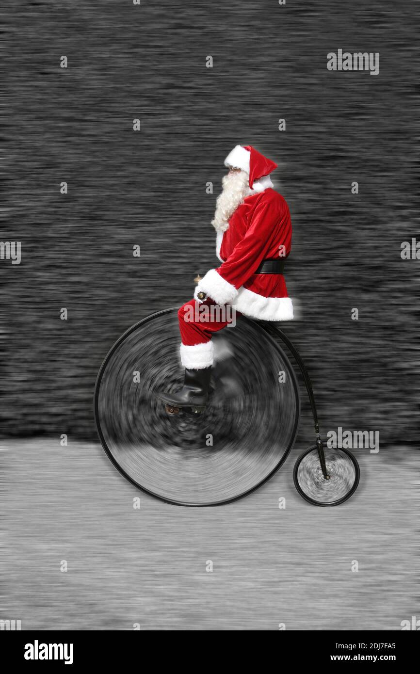 Padre Natale a cavallo di una bicicletta Penny Farthing Foto Stock