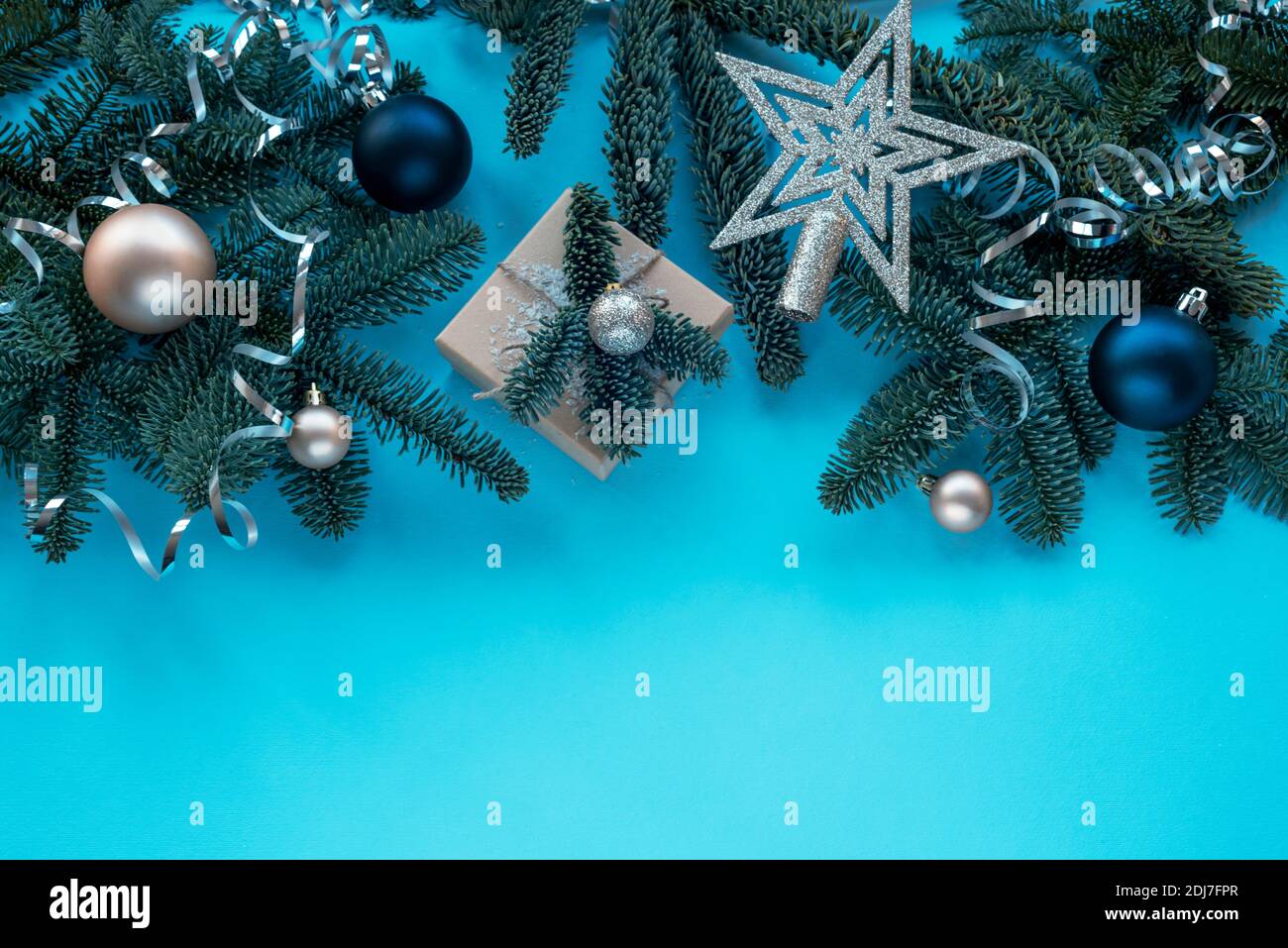 Rami di abete, regalo in scatola e baubles su sfondo blu. Concetto di Natale. Vista dall'alto, disposizione piatta, spazio per la copia. Foto Stock