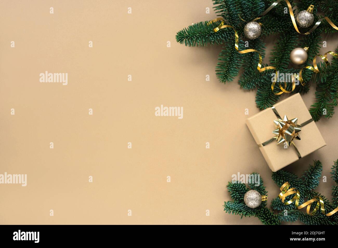 Rami di abete, regalo in scatola e baubles su sfondo beige. Concetto di Natale. Vista dall'alto, disposizione piatta, spazio per la copia. Foto Stock