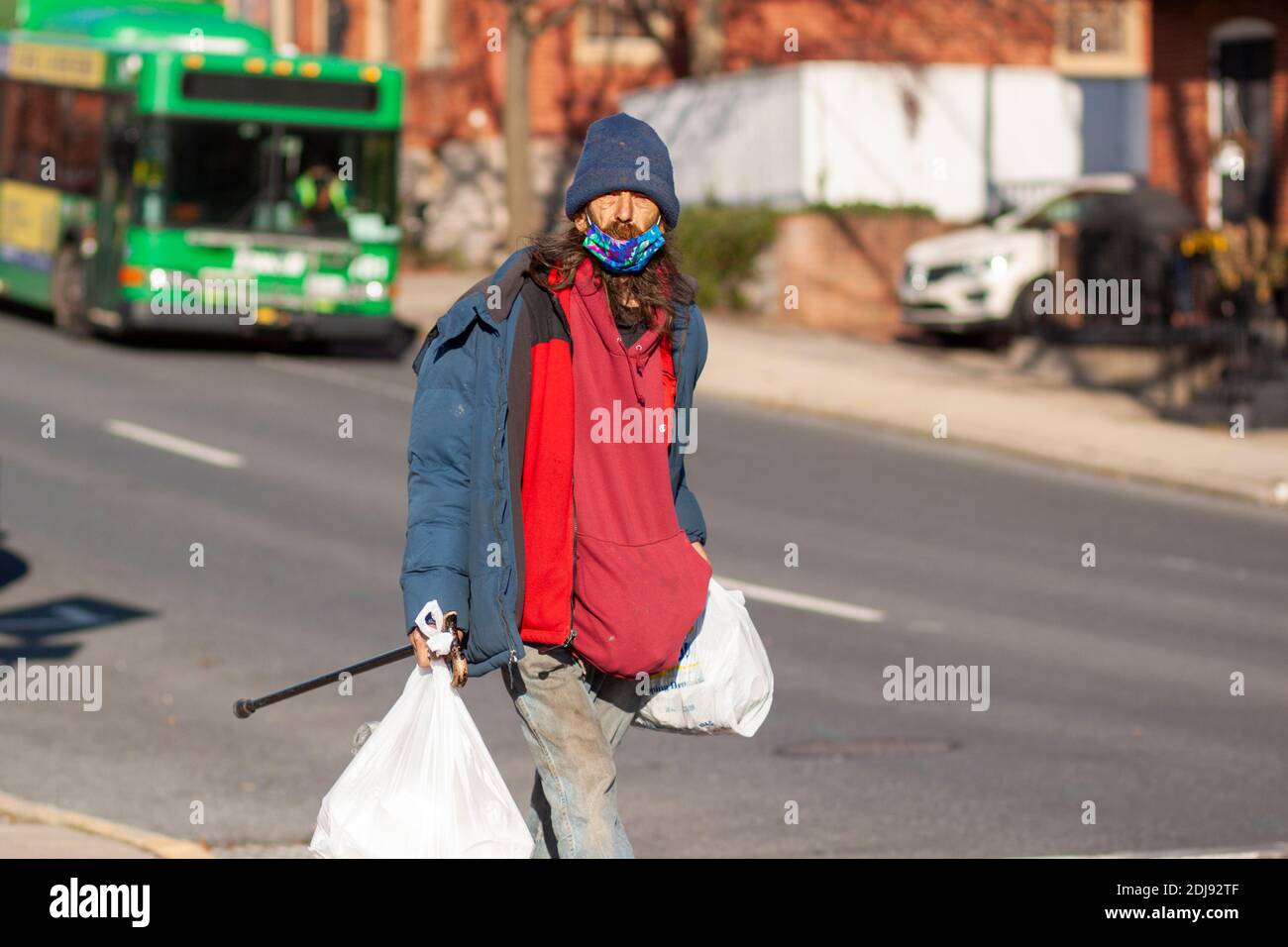 Frederick, Maryland, USA 11-22-2020: Un uomo senza casa caucasico dai capelli lunghi sta camminando nella strada nel centro di Frederick indossando sporco vecchio coagulo invernale Foto Stock