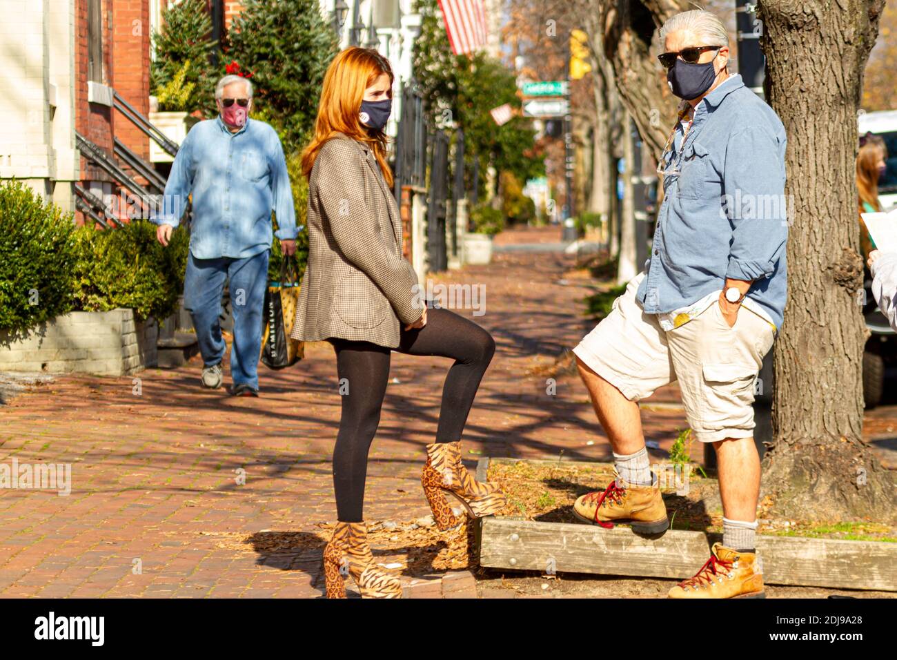 Alexandria, VA, USA 11-28-2020: Una giovane ed elegante donna con capelli rossi e suo padre che indossa abiti e stivali casual parlano all'aperto in una giornata di sole. Loro Foto Stock