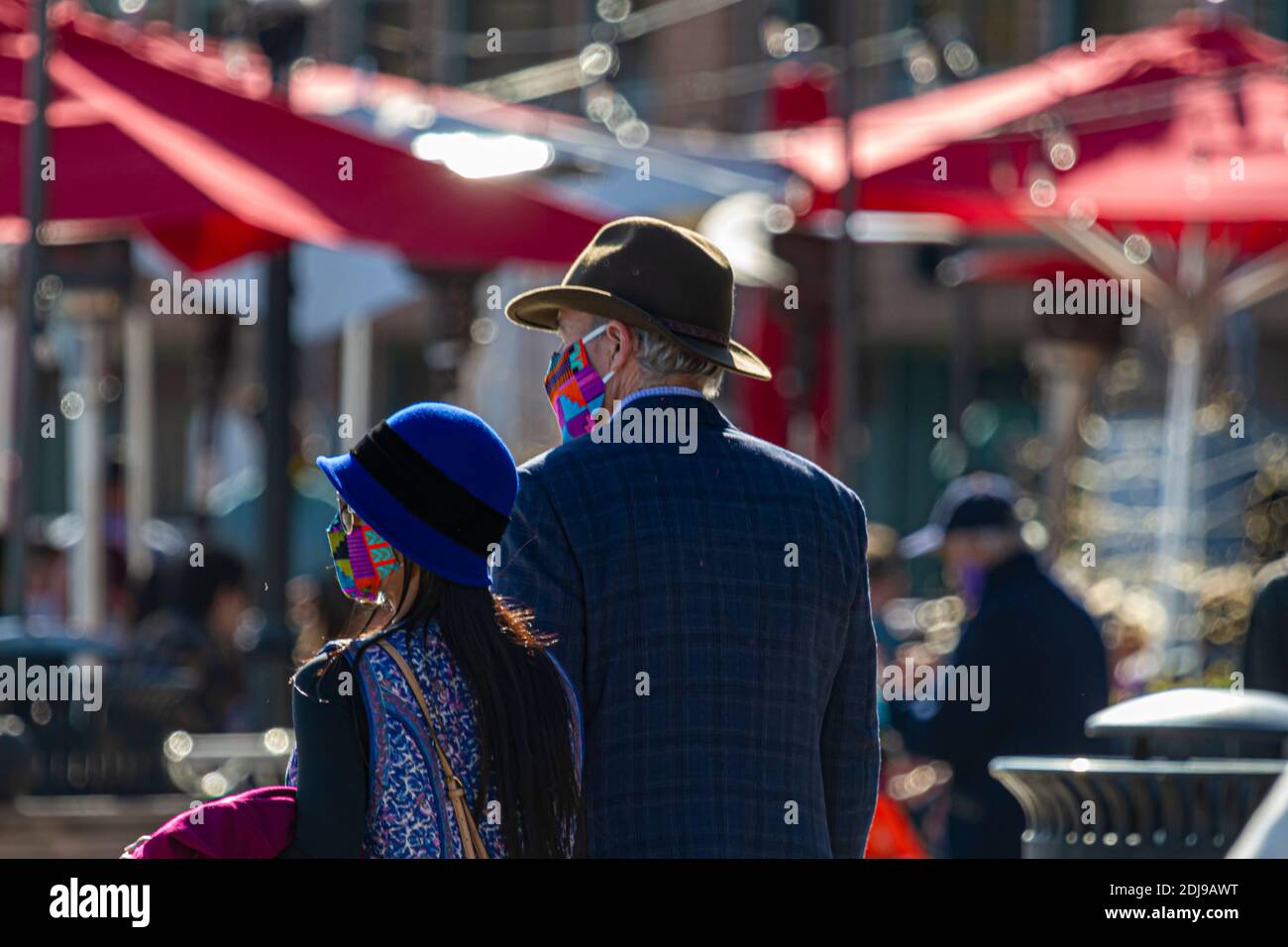 Alexandria, VA, USA, 11-28-2020: Un uomo caucasico anziano che indossa cappello e giacca da cowboy sta camminando sul lungomare in una giornata di sole con il suo più giovane w Foto Stock