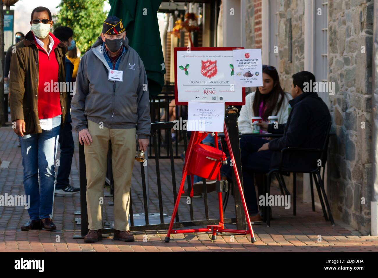 Alexandria, VA, USA 11-28-2020: Un veterano anziano con un cappello laterale dell'airman sta levandosi in piedi vicino ad un secchio di donazione dell'esercito di salvezza. Indossa il viso mas Foto Stock
