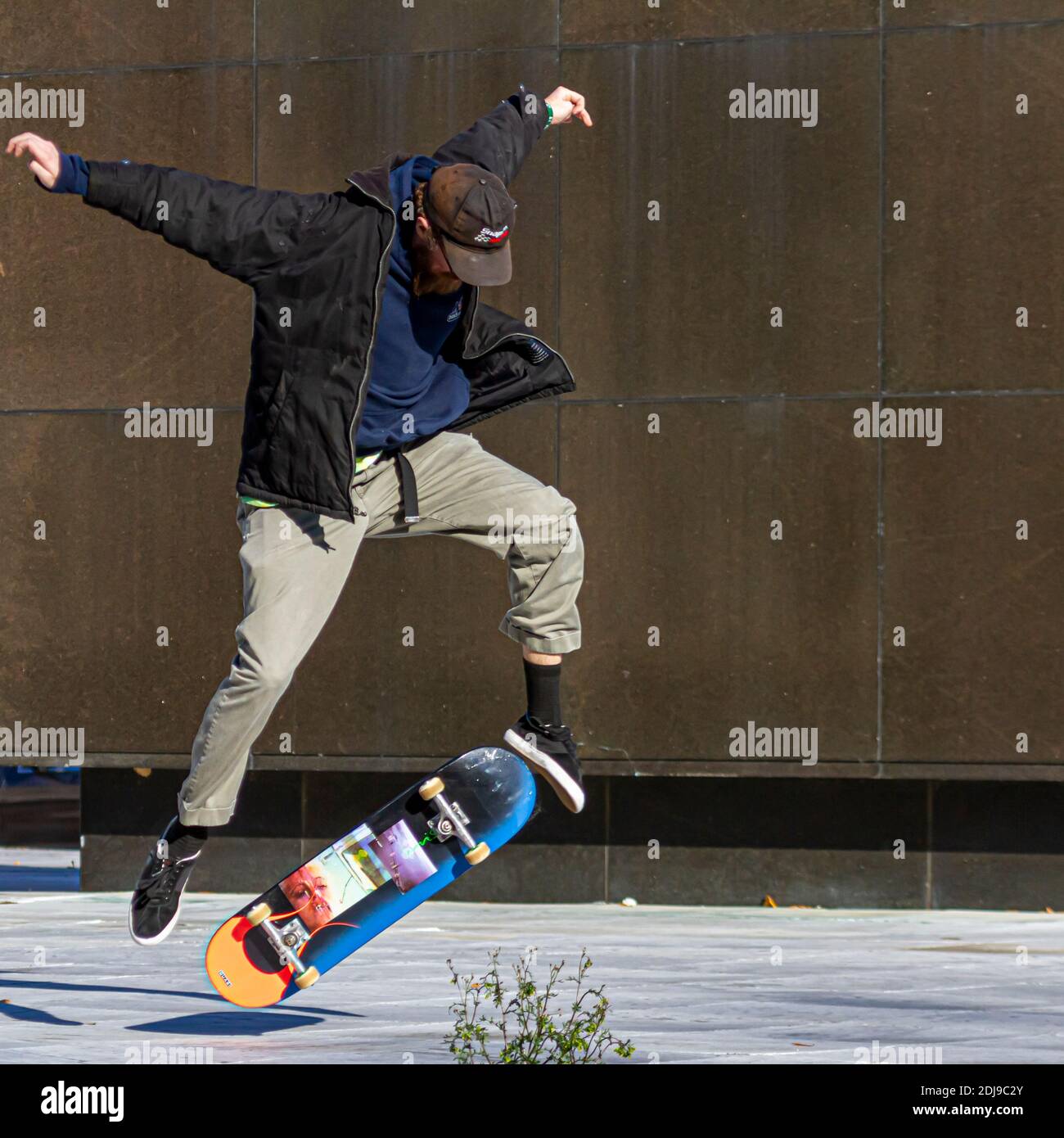 Washington DC, USA 11-28-2020: Un giovane uomo caucasico che indossa cappello, pantaloni in tela e un cappotto sta facendo una rotazione di 360 con skateboard. Salta nell'ai Foto Stock