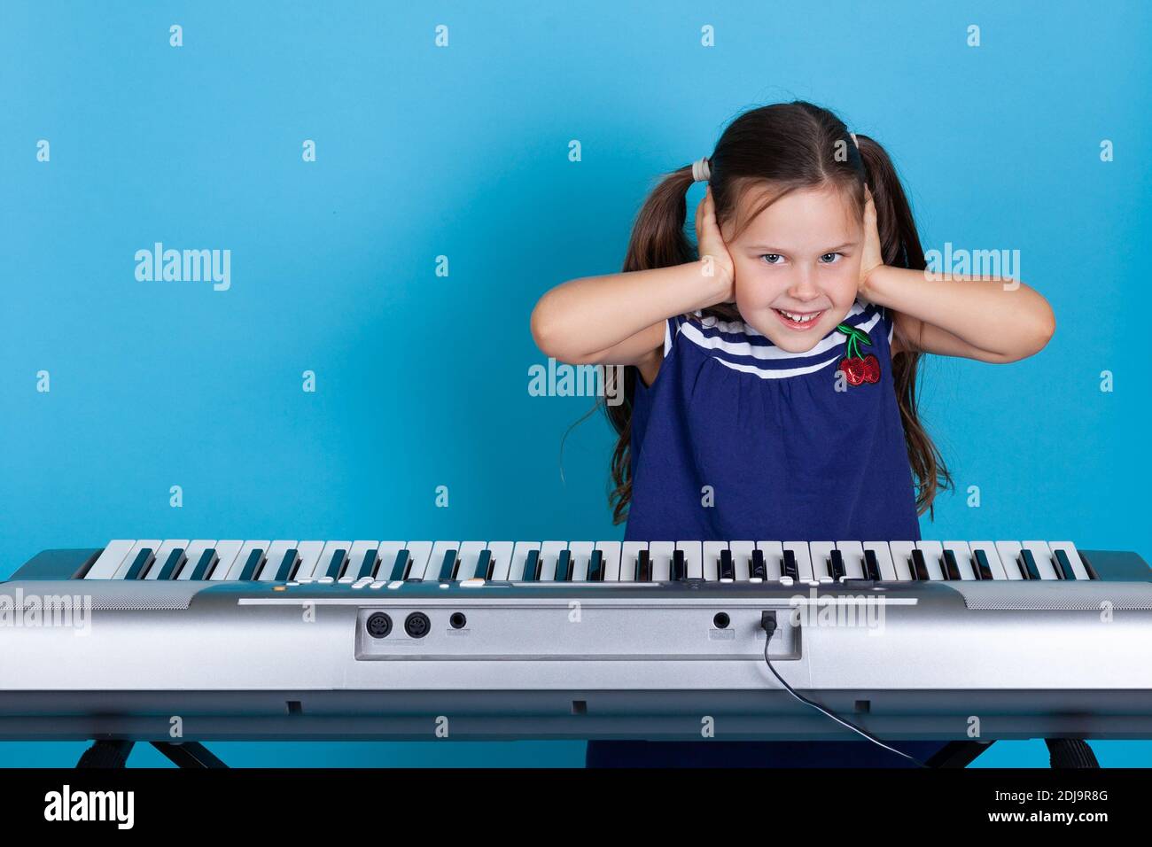 mock-up ritratto di una ragazza felice che copre le orecchie con le mani, indulge in lezioni di musica e vuole silenzio Foto Stock