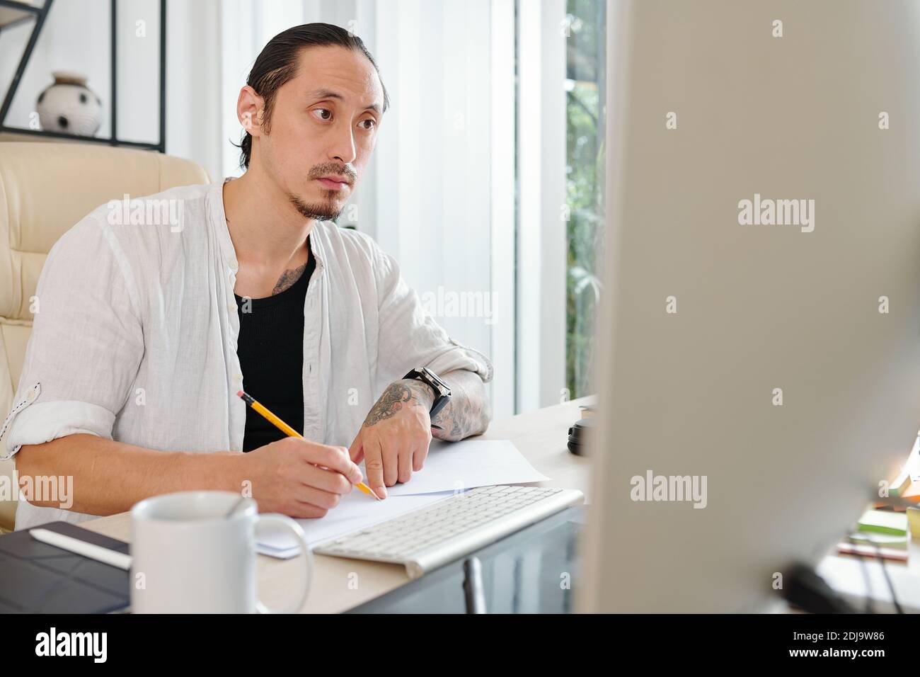Progettista grafico che legge l'e-mail dal cliente e disegno schizzo con matita Foto Stock
