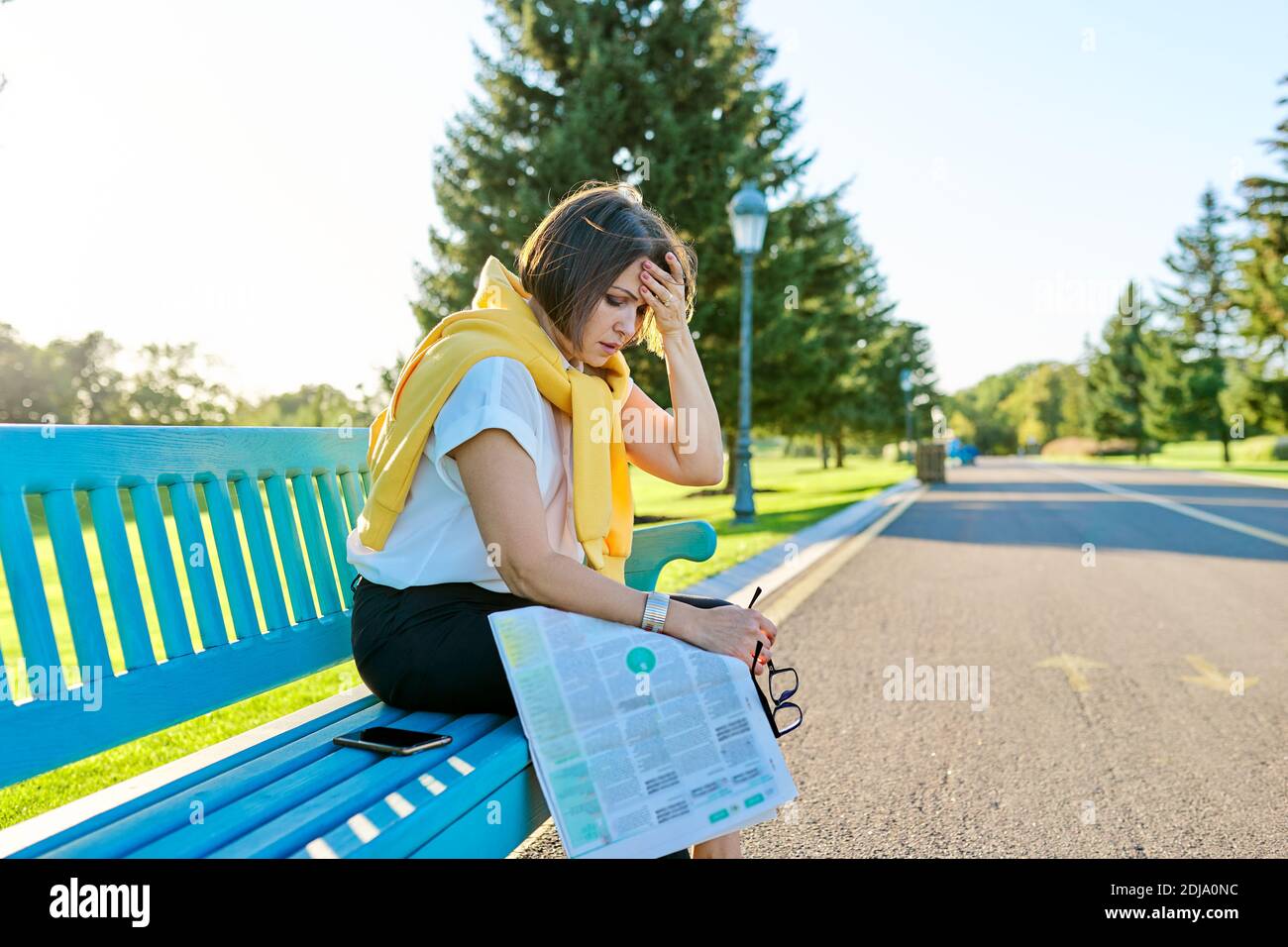 Stanca triste donna matura seduta su panchina nel parco, copia spazio Foto Stock