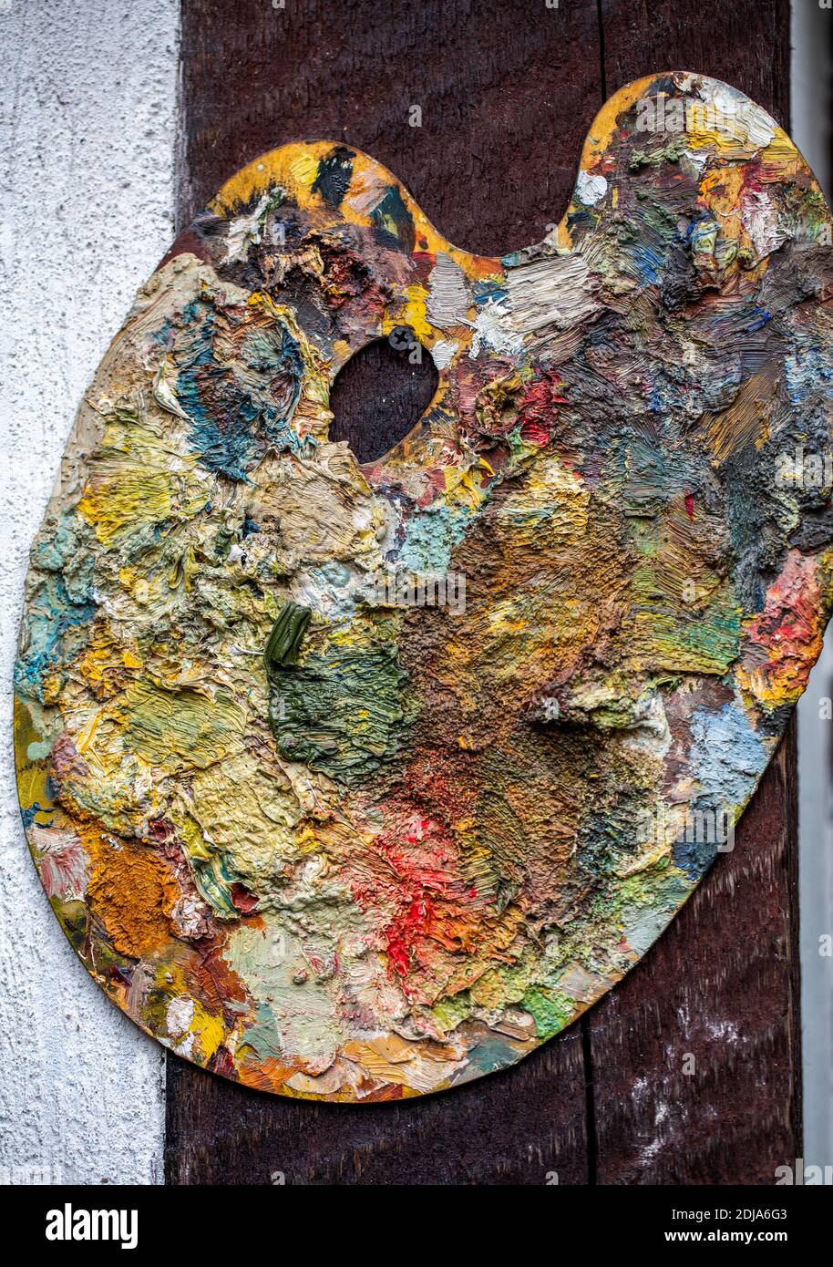 tavolozza del pittore ricoperta da colori di vernice vivaci e misti. Uno sfondo astratto dipinto Foto Stock