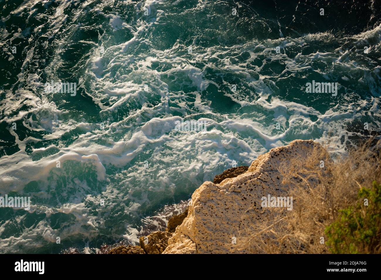 Vista aerea di una scogliera e delle onde che colpiscono la riva in una giornata luminosa e soleggiata Foto Stock