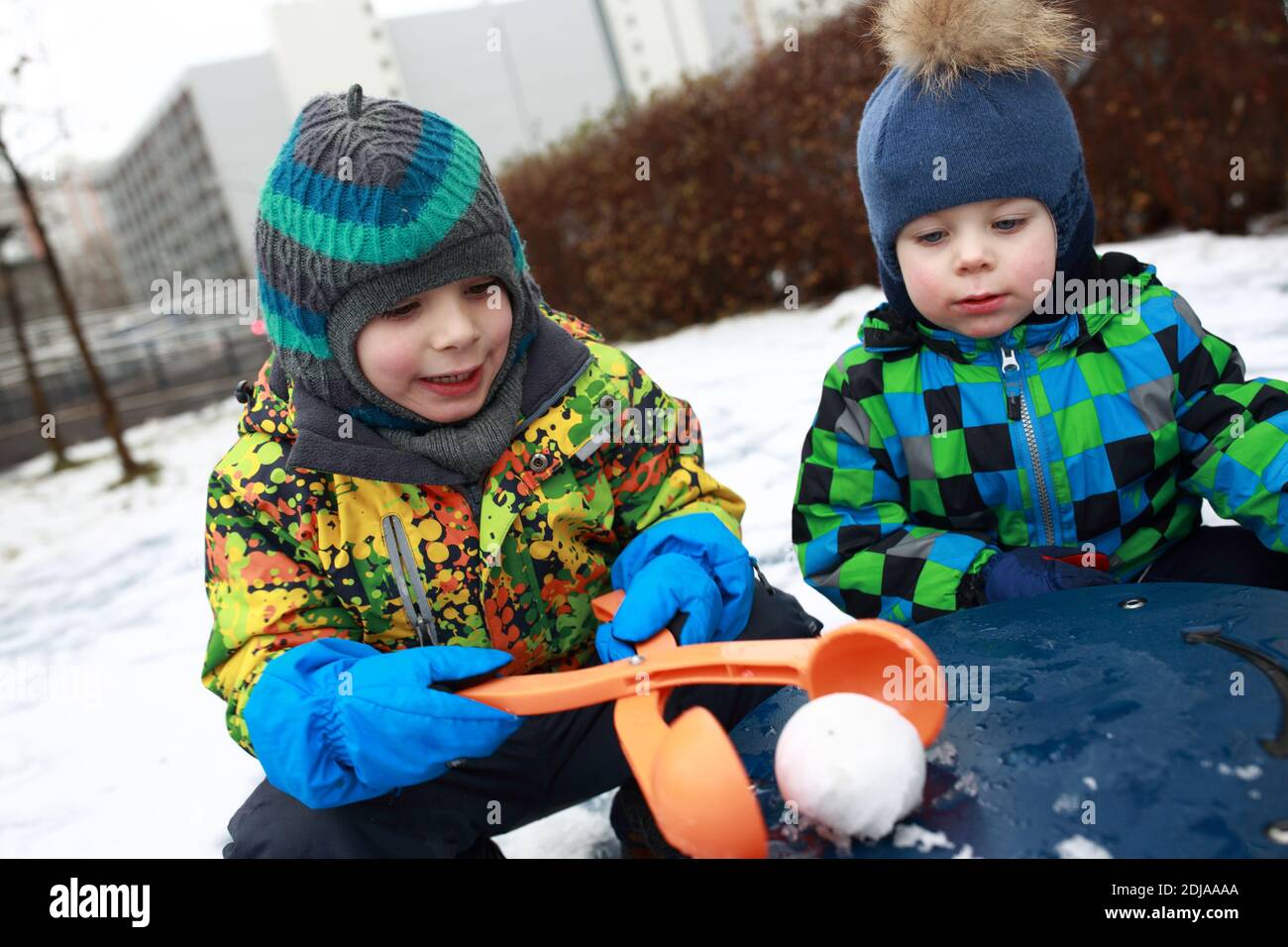 Ragazzi che giocano con un produttore di palla di neve nel parco giochi Foto Stock